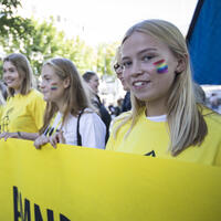 Ungdommer på Pride står bak et Amnesty-banner og smiler til kamera. 